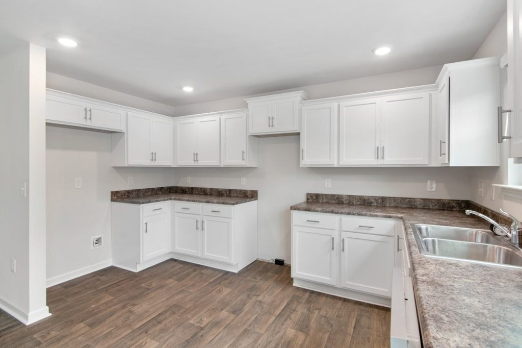 furniture-in-kitchen-4832513 Spacious modern kitchen featuring white cabinetry, wooden floors, and natural lighting. Ideal for contemporary homes.